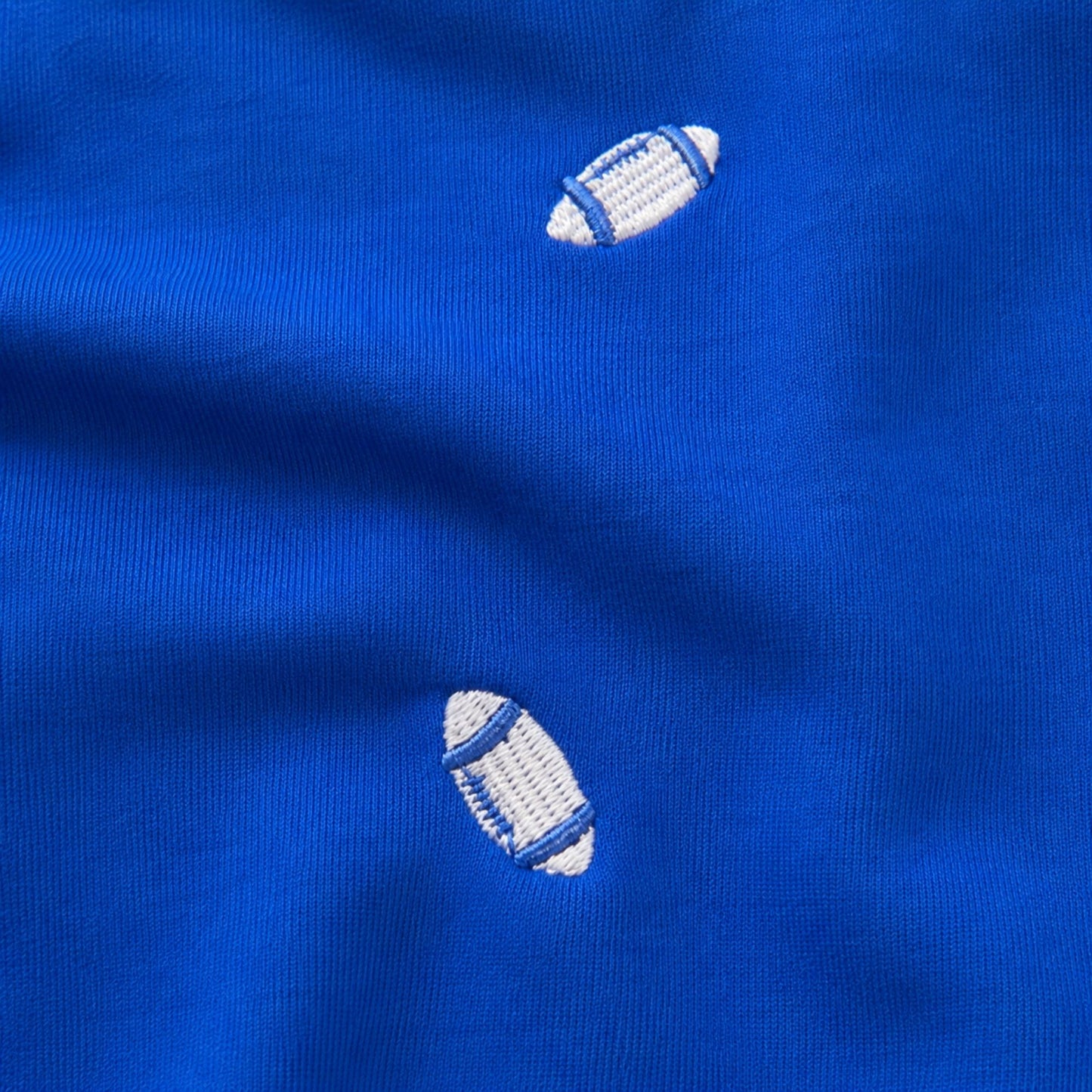 Woman wearing the Air Force blue Football Season Embroidered Blouse with allover white football embroidery