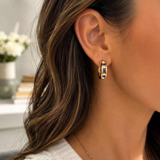 Gold-tone hoop earrings with alternating blue and clear rhinestones