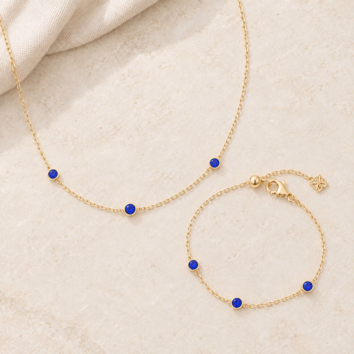 Academy Gemstone Necklace & Bracelet with three royal-blue glass stones set along a delicate 18K gold-plated chain.