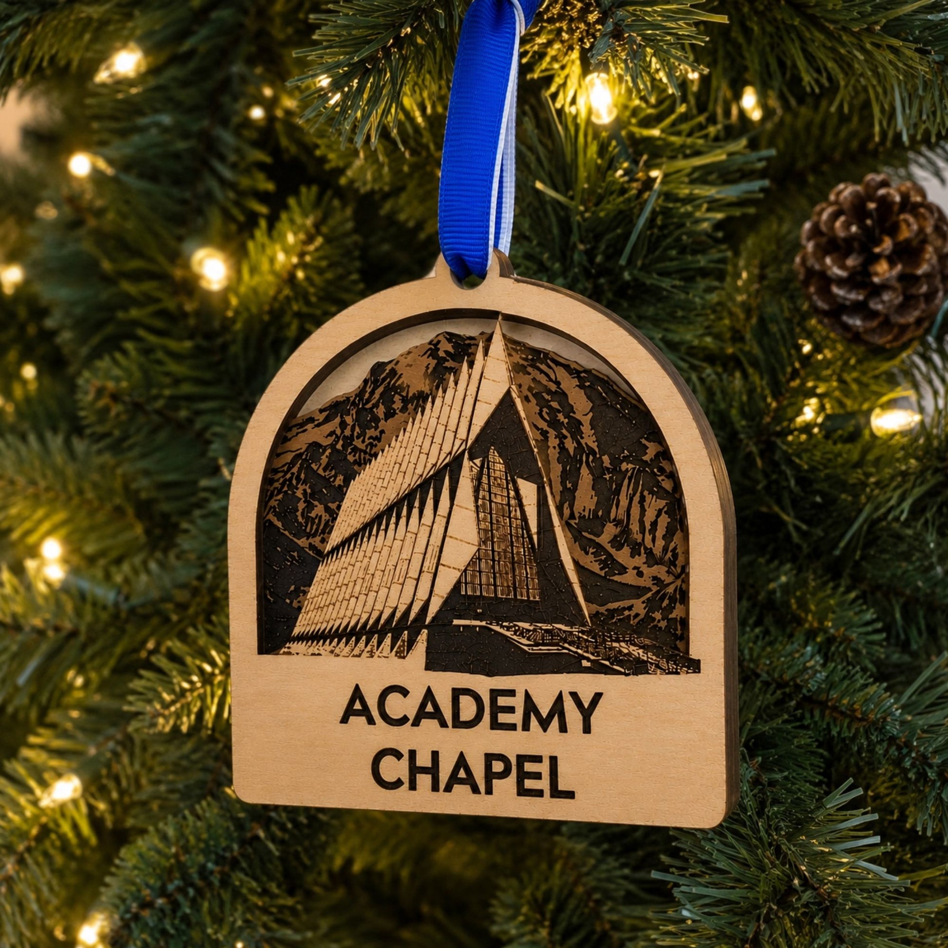 Cherry wood Academy Chapel ornament featuring a detailed laser-engraved design of the United States Air Force Academy Chapel with a royal blue hanging ribbon.