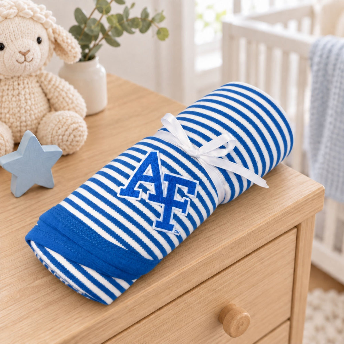 Rolled Academy Striped Baby Blanket with embroidered AF logo displayed in a nursery setting