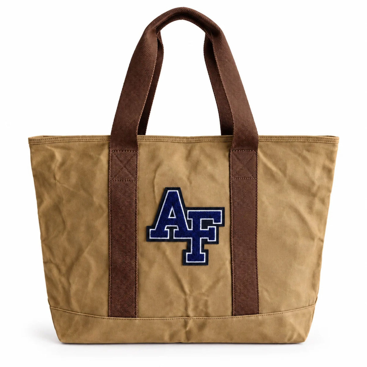 Front view of the tan Air Force Academy canvas boat tote featuring a navy chenille AF patch, brown cotton handles, and structured canvas design.