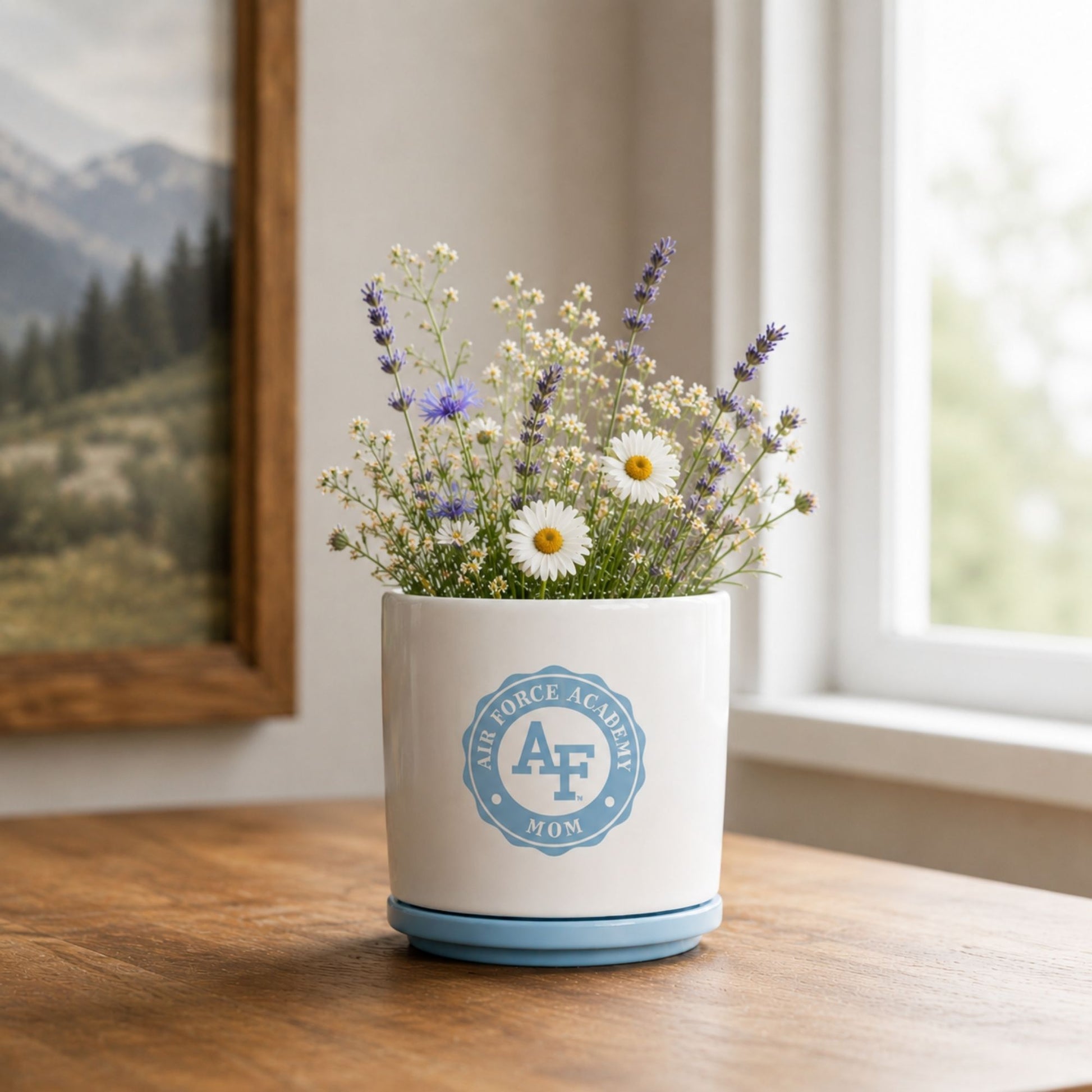 White ceramic Air Force Academy Mom planter with a cloud blue drainage plate featuring the Air Force Academy Mom emblem.