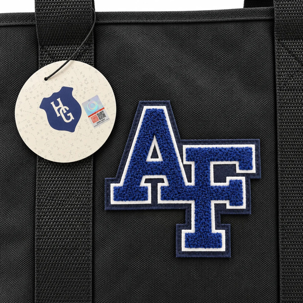 Close-up of the Air Force Canvas Boat Tote featuring a blue and white chenille AF patch on charcoal canvas with Heritage Gear hang tag.