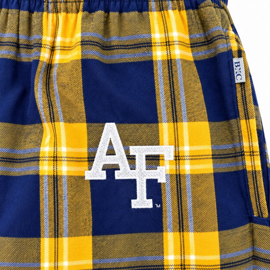 Close-up of white embroidered AF logo on gold and navy plaid pajama pants, with side pocket detail.