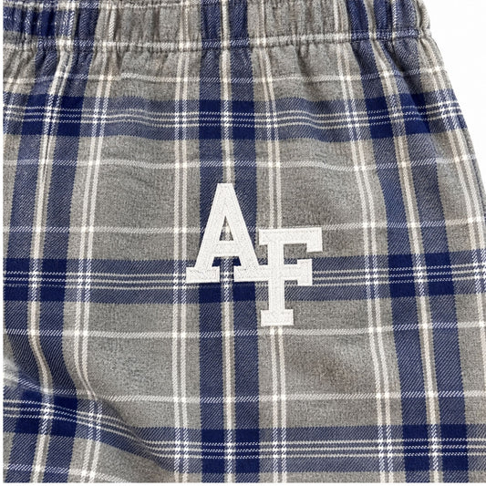 Close-up of white embroidered AF logo on silver-gray pajama pants with navy and white plaid.