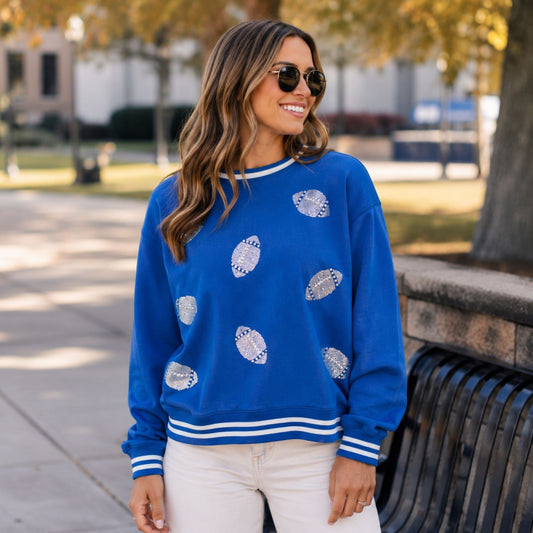 Woman wearing the royal blue Falcon Football Bling Crewneck with silver sequin football details