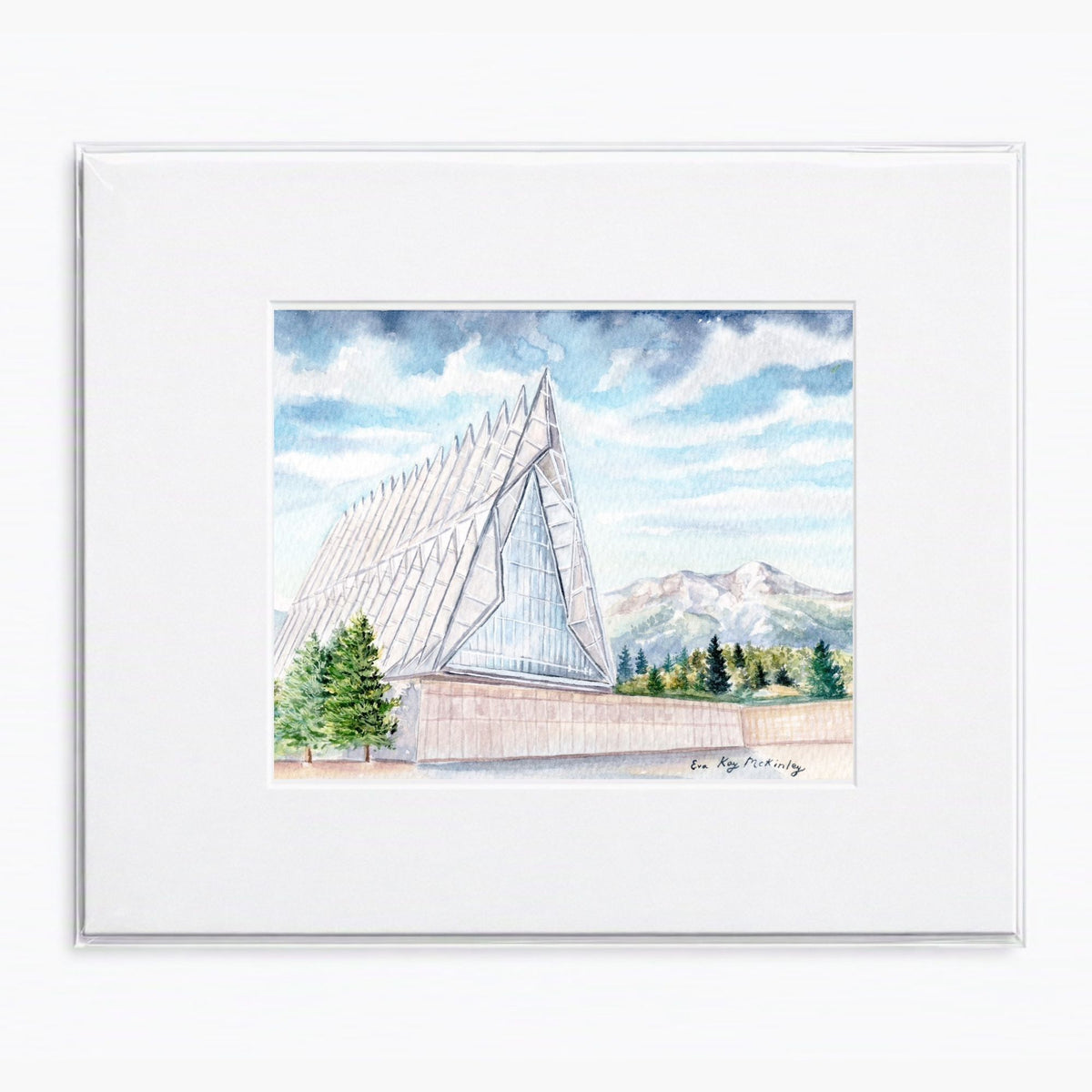 Matted watercolor painting of the USAFA Cadet Chapel with the Rocky Mountains in the background.
