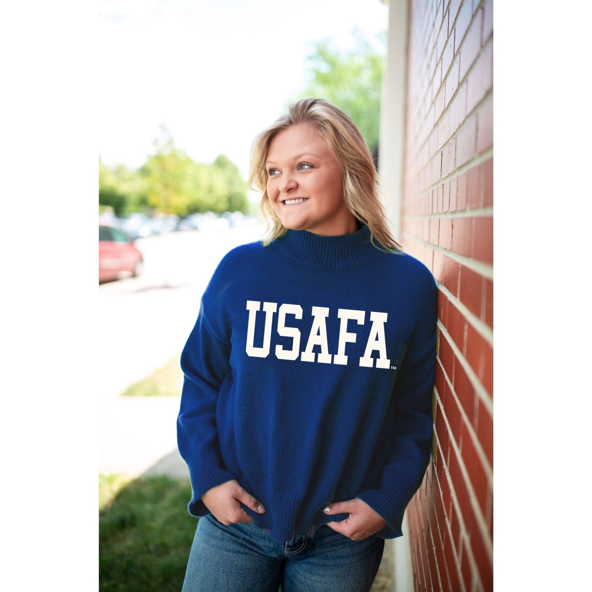 Model wearing a royal blue USAFA cozy knit turtleneck sweater with white USAFA lettering
